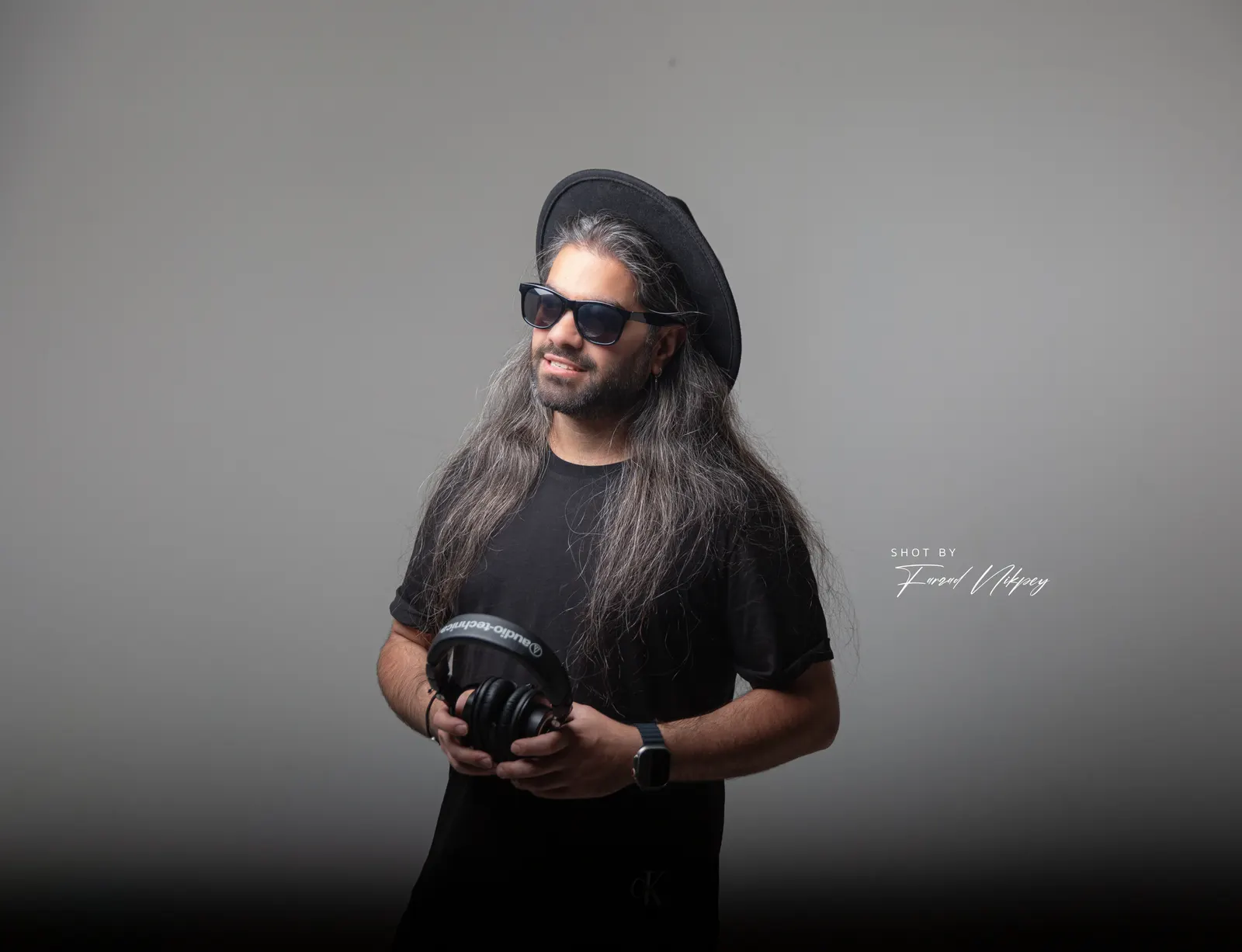 DJ Mahbod in a hat holding his headphones