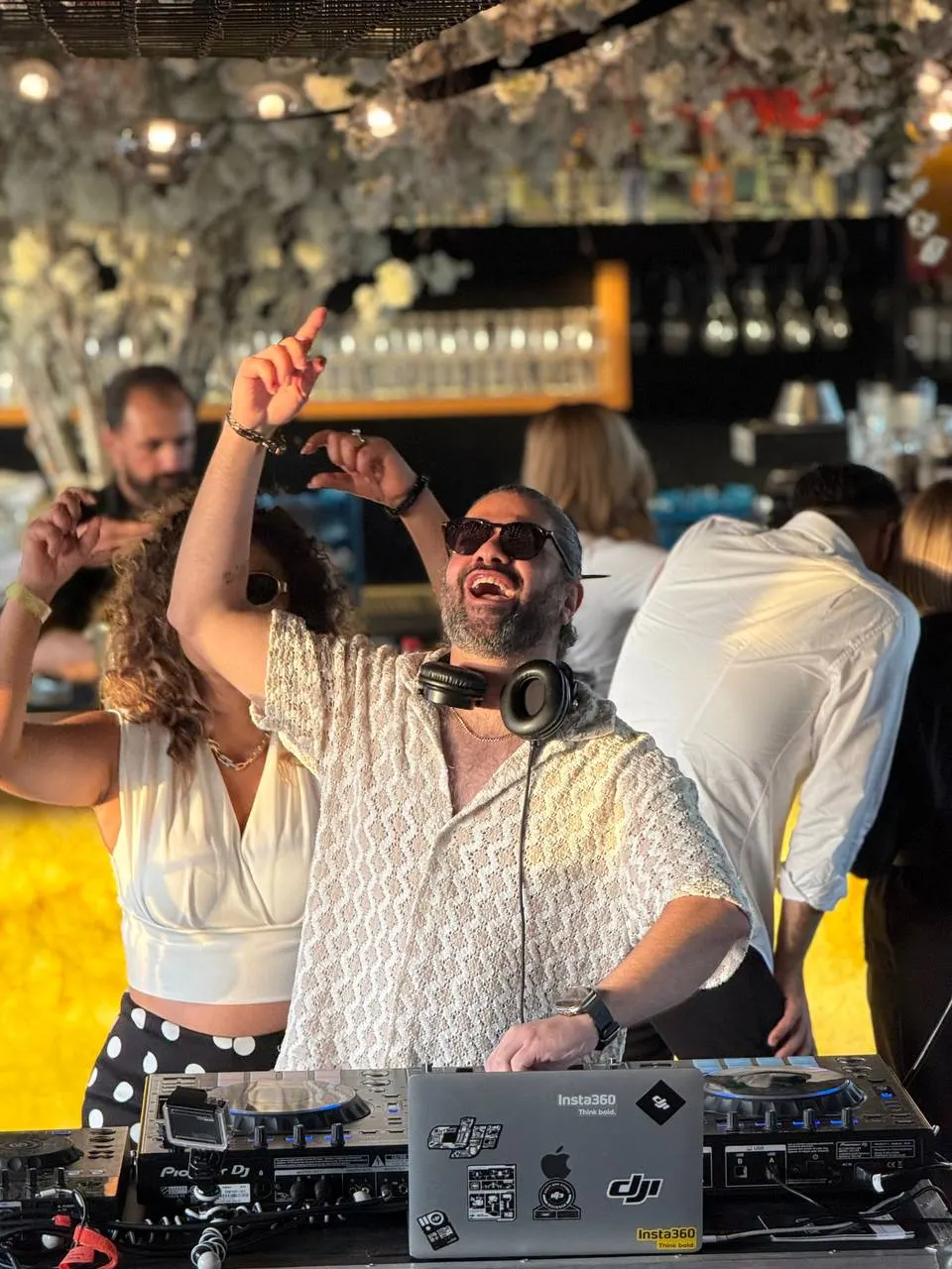 DJ Mahbod with his arm raised at a daytime rooftop party